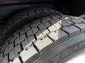 A close-up of two large, worn tires from a 1994 Freightliner FL80 showing deep tread patterns and distinct markings on the sidewall