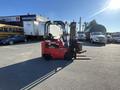 A red 2013 Raymond forklift with black forks positioned for lifting pallets