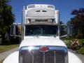 A front view of a 2008 Peterbilt 335 truck featuring a prominent chrome grille and dual side mirrors with a white cab and air conditioning unit on top