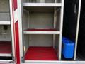 A 1994 Freightliner FL80 with empty storage compartments featuring metal shelves and red rubber flooring