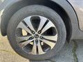 Close-up of a five-spoke alloy wheel on a 2012 Kia Sportage with visible dirt and wear on the tire and wheel surface