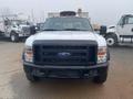 A 2009 Ford F-450 Super Duty truck with a silver body and black grille in a front view showcasing its headlights and log cabin design