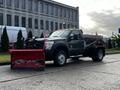 A 2012 Ford F-550 truck equipped with a large red snow plow attached to the front and a black dump bed at the rear