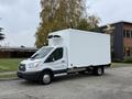 A 2018 Ford Transit with a white cargo box and refrigeration unit on top parked on a roadside