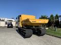 A yellow 2022 TerraMac RT7R with tracks and a large dumping bed is parked in an industrial area showcasing its rugged build and design