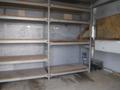 An empty shelving unit with multiple metal shelves and a wooden base inside a 2010 Forest River Enclosed vehicle