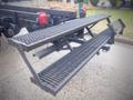 A metal step platform with a textured surface attached to a truck's rear, designed for easier access to the cargo area