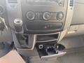 Interior dashboard of a 2017 Mercedes-Benz Sprinter featuring climate control knobs a gear shift and a cup holder