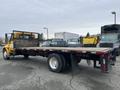 A 2007 International 4300 flatbed truck with a yellow cabin and a wooden flatbed in the foreground