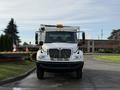 A 2015 International DuraStar 4300 truck facing forward with a white exterior and orange cab lights