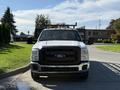 A 2016 Ford F-350 SD pickup truck with a white exterior and a black grille is facing forward showcasing its front features and amber lights on top