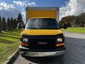 A yellow 2017 GMC Savana truck with a large storage box attached at the back facing the viewer