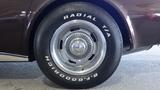 A close-up of a 1971 Chevrolet Corvette Stingray wheel featuring a polished chrome rim and a white-lettered Radial T/A tire with a classic design