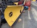 A yellow Fisner XV2 snowplow blade with a black splatter design and rugged edge placed on wooden supports