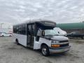 A 2017 Chevrolet Express bus with a black front and white body is parked with its side door open