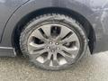 A close-up of a gray alloy wheel from a 2014 Subaru Impreza with a tire showing slight wear and a wet surface