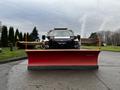 A 2009 Ford F-550 with a large red snow plow attached at the front facing forward