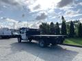 A 2013 Ford F-450 SD flatbed truck with a black bed and white cab parked at an angle