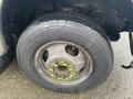 Close-up of a tire mounted on a wheel with green lug nut covers on a 2012 Chevrolet Express van