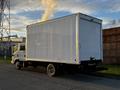 A white 2017 Isuzu NPR box truck with a closed cargo area and visible exhaust smoke emanating from the rear