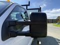 A close-up of the side mirror of a white 2016 Ford F-350 SD pickup truck