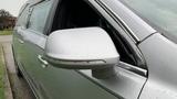 A silver 2013 Lincoln MKT with a side mirror reflecting raindrops