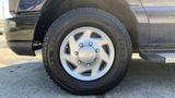 A close-up view of a silver wheel with a multi-spoke design and a black tire mounted on a 2013 Ford Econoline