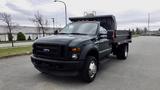 A 2008 Ford F-450 Super Duty truck with a flatbed and a dark green exterior positioned in a parking area