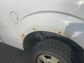 The image shows the rear wheel area of a 2009 Ford F-150 with noticeable rust on the fender and a portion of the undercarriage visible along with a rugged tire tread