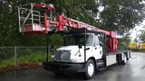 A 2010 International 4300 truck with a large red aerial lift mounted on the chassis and a bucket at the end of the arm