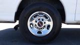 A close-up of a chrome wheel from a 2012 GMC Savana showcasing a distinctive GMC logo on the center cap and a large tire with an aggressive tread pattern