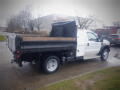 A 2008 Ford F-550 pickup truck with a flatbed and wooden siding parked on a wet surface