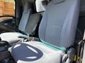 Interior view of a 2016 Isuzu NPR with two gray seats visible one with a black seat cover and seatbelt on the side of the driver's area