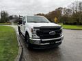 A white 2020 Ford F-350 SD pickup truck with black accents and a flatbed design parked on a grassy area