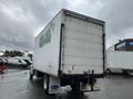 A white 2008 Hino Conventional Cab truck with a large cargo box is parked, featuring visible wear and graffiti on the rear of the truck