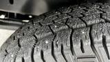 Close-up of a worn tire tread showcasing deep grooves and small metal studs designed for enhanced traction and grip on various surfaces