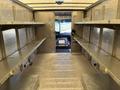 Interior view of a 2011 Ford Econoline van featuring metal shelving on both sides and a clear aisle leading to the front cab