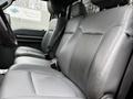 Interior view of a 2011 Ford F-250 SD featuring gray leather front seats with seat belts and a spacious seating arrangement