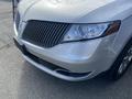 A silver 2013 Lincoln MKT with a distinctive grille and prominent headlights is shown from the front, showcasing its sleek design and elegant features