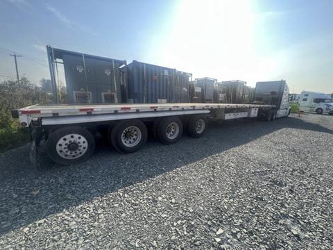 A 2013 Lode King flatbed truck loaded with several metal containers on a gravel surface