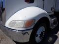 A white 2008 Peterbilt 335 truck with a shiny chrome bumper and a partially cloudy headlight