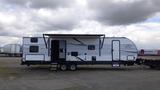 A 2021 Forest River 312BH East To West Della Terra travel trailer with a white and gray striped exterior and awning extended