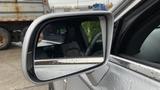 A side mirror of a 2013 Lincoln MKT displaying reflections and raindrops on its surface