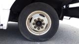 Close-up of the wheel of a 2011 Ford Econoline showing a white rim with rusted lug nuts and a worn black tire