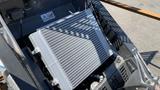 A close-up view of the radiator of a 2024 Agt Ktt23 Stand On Skid Steer Track Loader 23HP showing cooling fins and metal housing