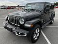 A 2019 Jeep Wrangler in black with distinctive front grille round headlights and rugged tires parked in a lot