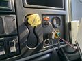 Dashboard controls of a 2007 International 7300 featuring a yellow parking brake lever a pressure gauge and various switches and connectors