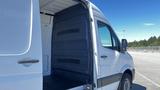 A 2016 Mercedes-Benz Sprinter van with an open rear, showcasing its spacious cargo area and interior paneling