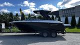 A 2023 Mercury Monterey boat, sleek black hull with a white stripe, equipped with a wakeboard tower, mounted on a dual-axle trailer