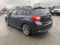 A 2014 Subaru Impreza hatchback in dark gray with alloy wheels and a sleek design showing the rear angle of the vehicle